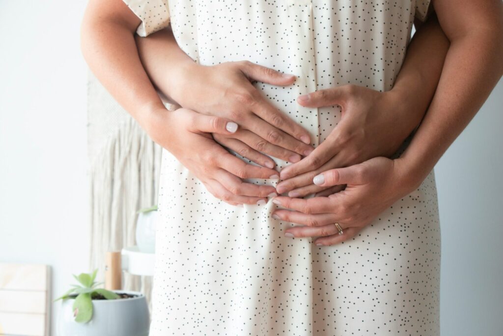 a father holding a mothers tummy suggesting childbirth in the future or motherhood