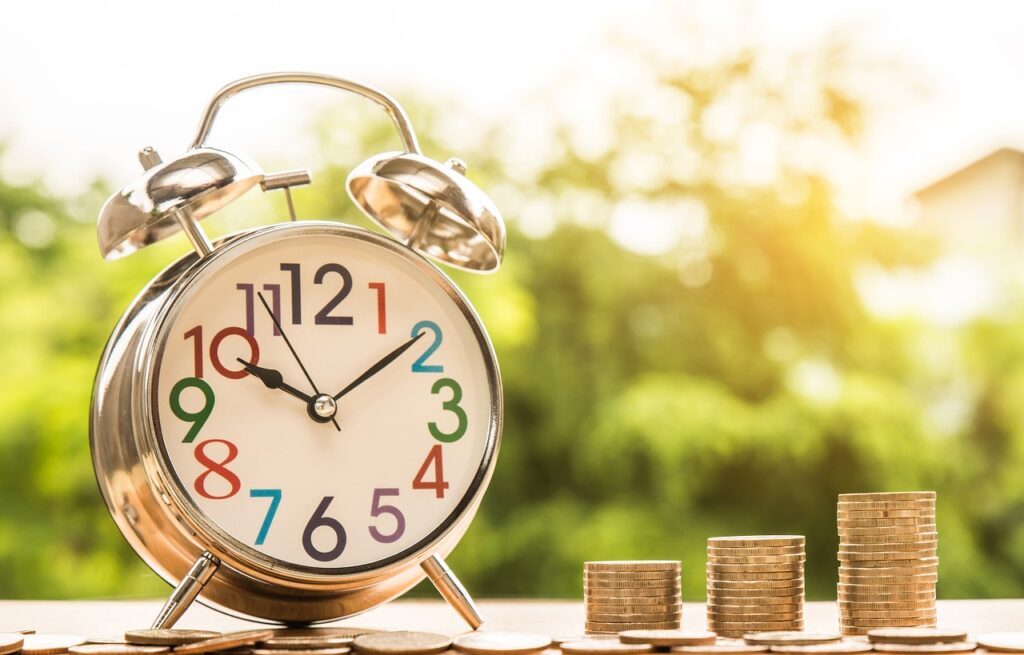 a clock with a pile of coins on the side to implicate time and money of being a seishain