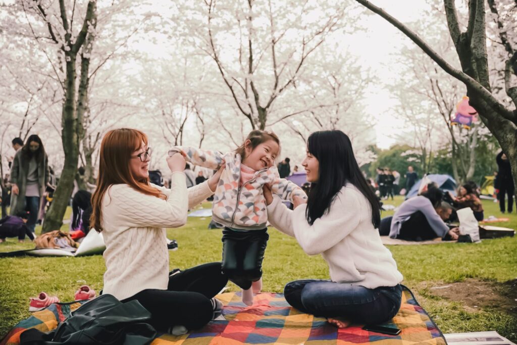 a family at a picnic with sakura blossoms at the background